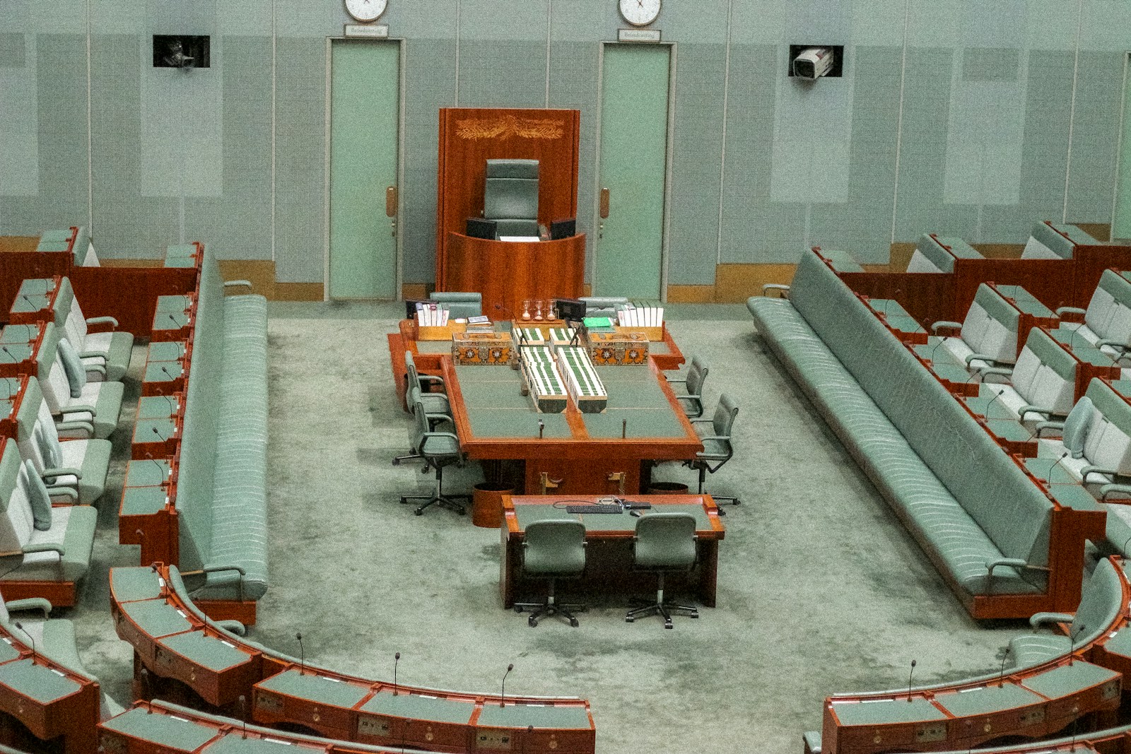 An empty parliamentary chamber with seating and a central table