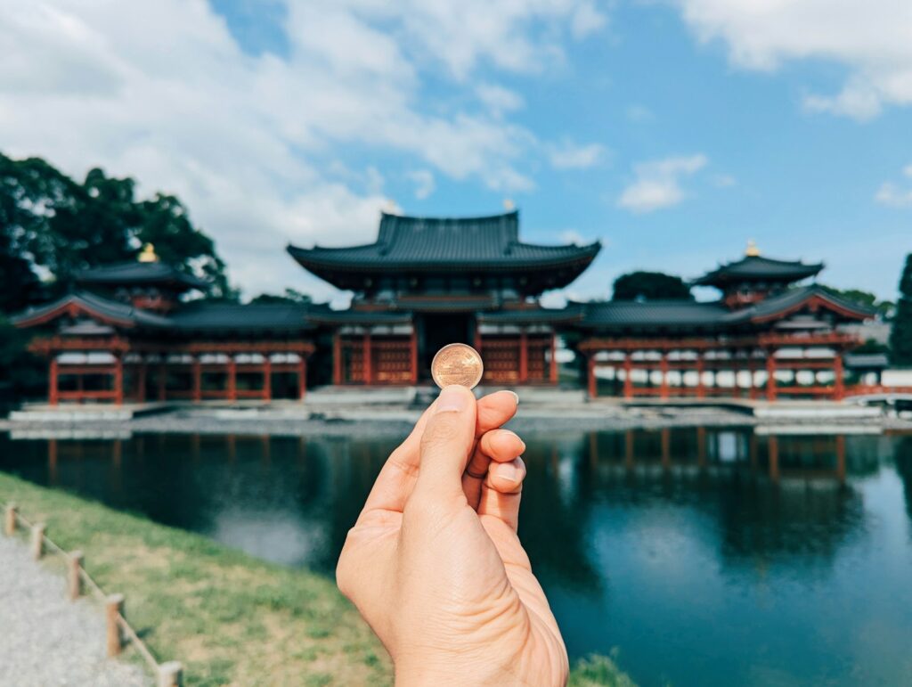 A hand holding a small piece of food in front of a body of water