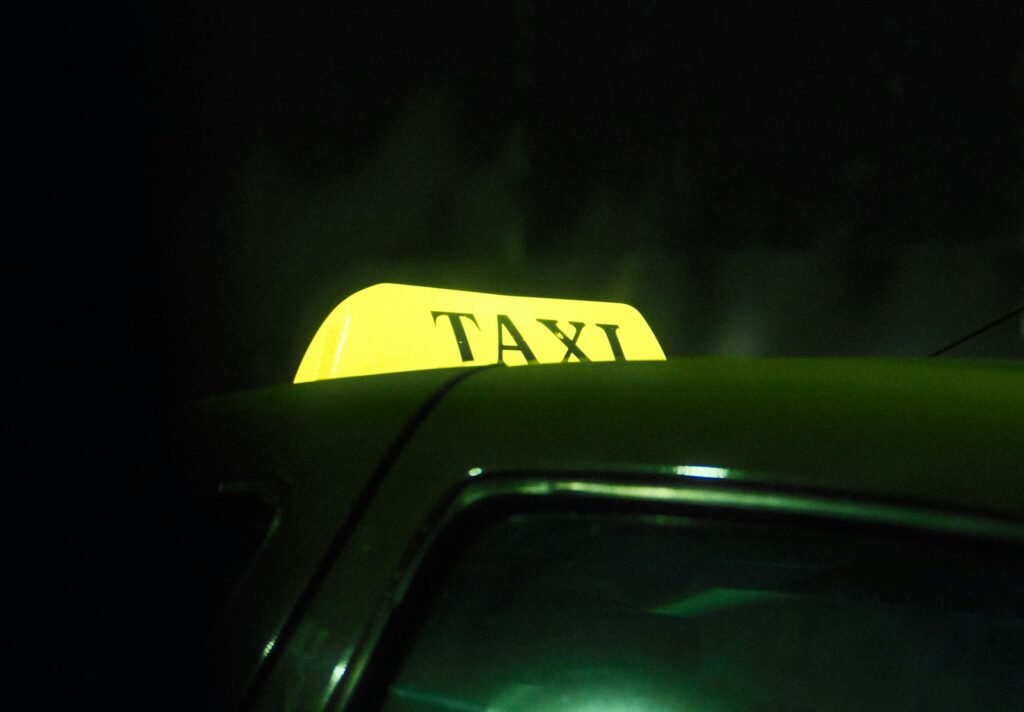 A yellow taxi sign on a car at night.